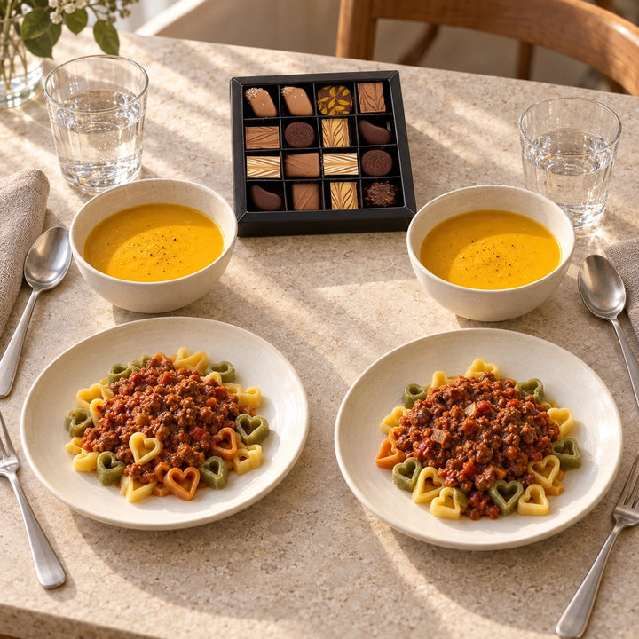 Serviervorschlag für Abend zu zweit mit zwei Portionen Möhren-Ingwer-Suppe, Herznudeln mit Bolognese und der Pralinenauswahl.