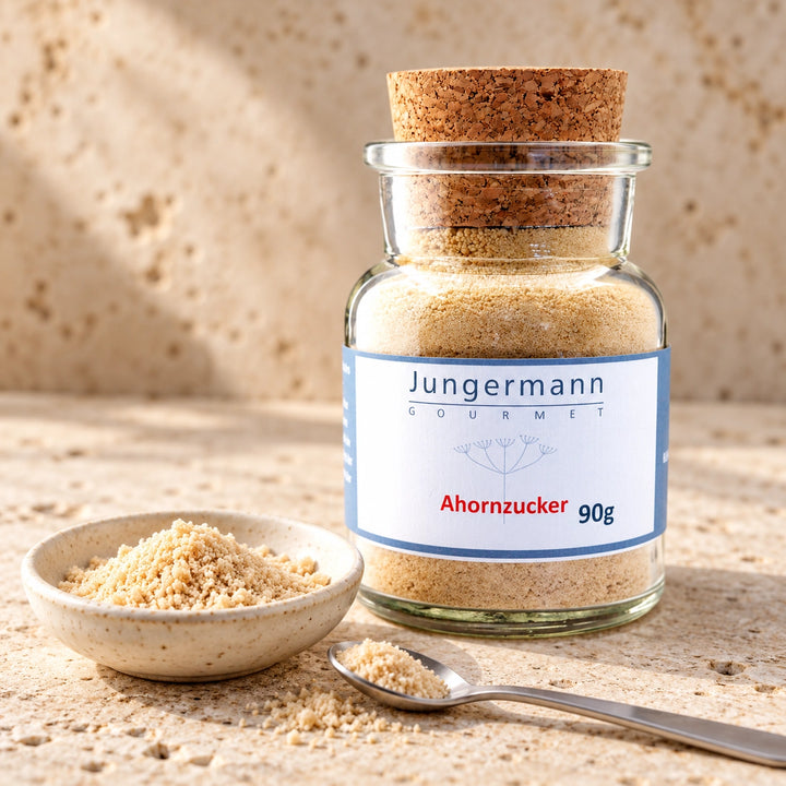 Ahornzucker von Jungermann Gourmet im Korkglas neben einer kleinen Schale und einem Teelöffel mit feinem Zucker auf hellem Naturstein.