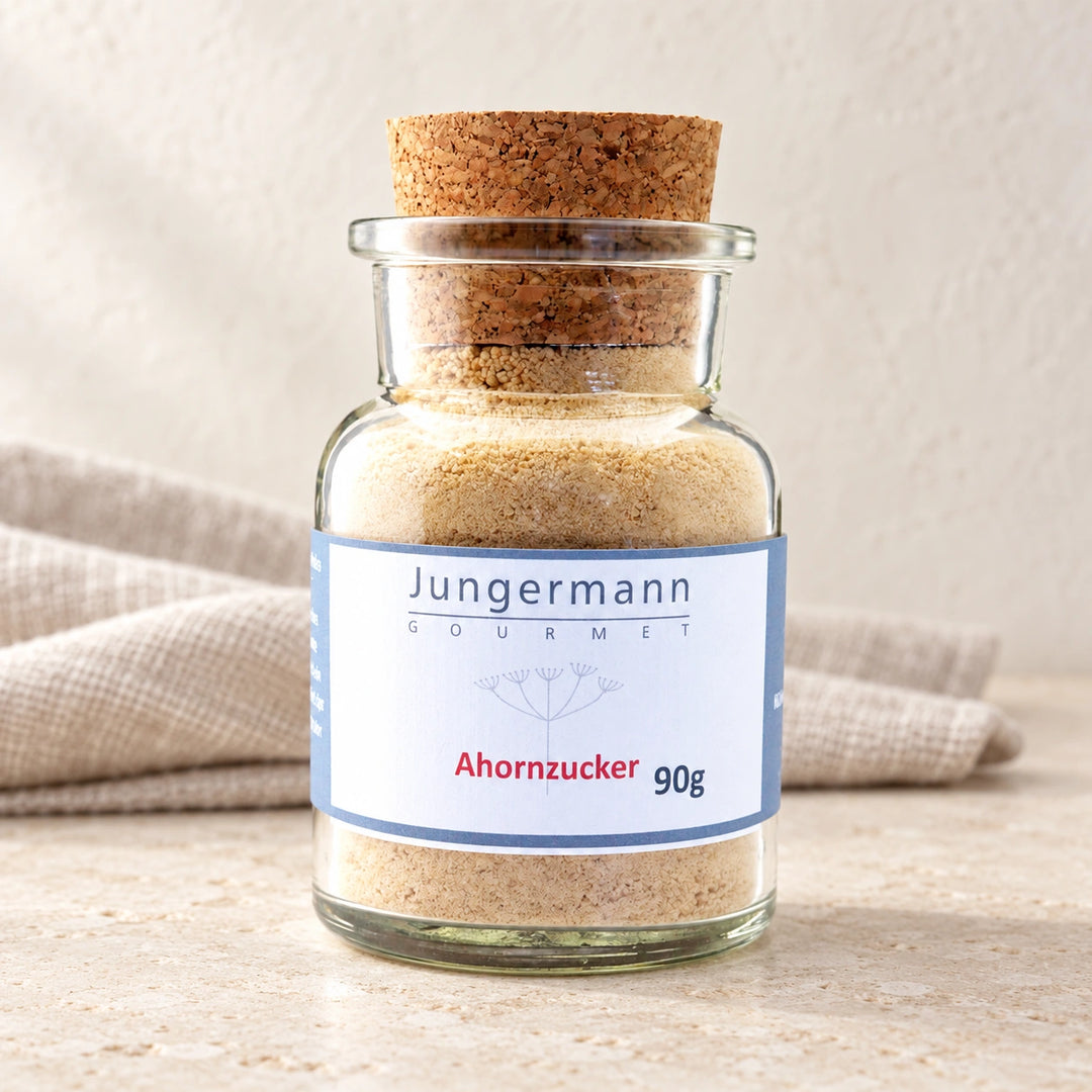 Ahorn-Zucker im originalen Korkglas mit blau gerahmtem Etikett auf hellem Naturstein.
