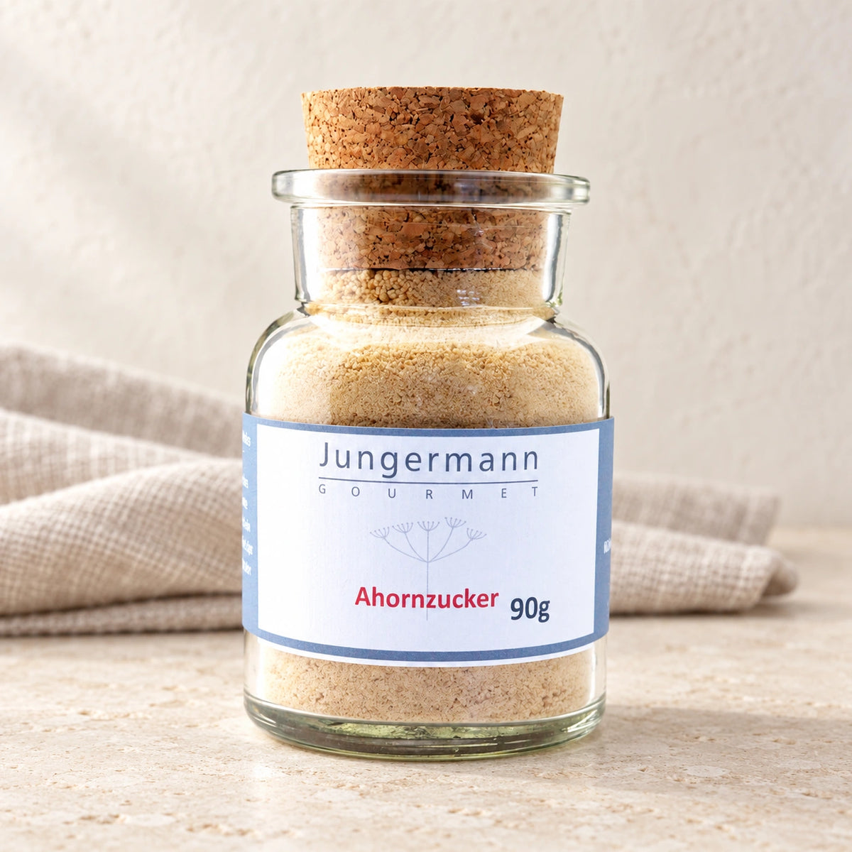 Ahorn-Zucker im originalen Korkglas mit blau gerahmtem Etikett auf hellem Naturstein.