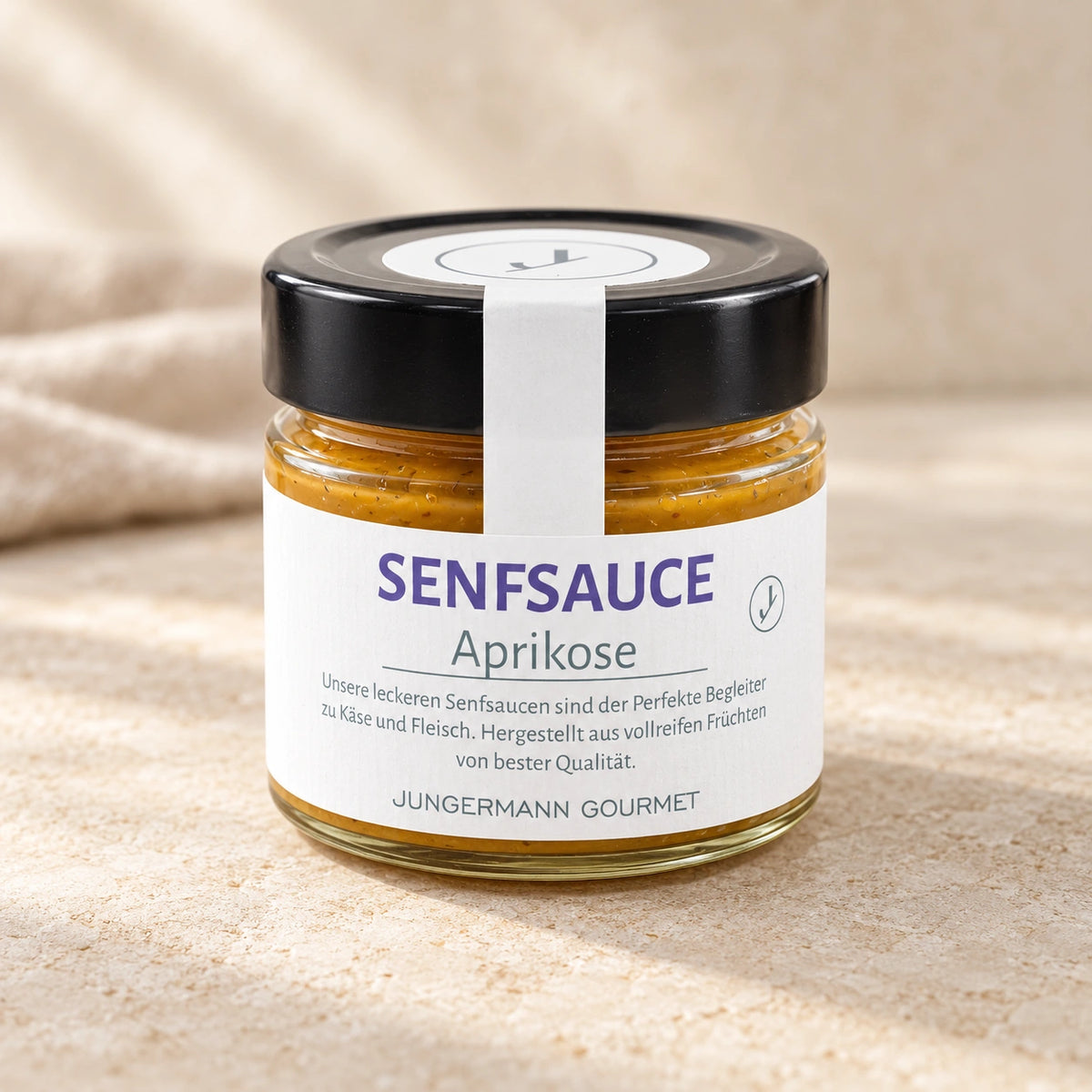 Aprikosen-Senf-Sauce von Jungermann Gourmet im Glas mit schwarzem Deckel, weißem Siegelstreifen und vollständig sichtbarem Etikett auf Naturstein.