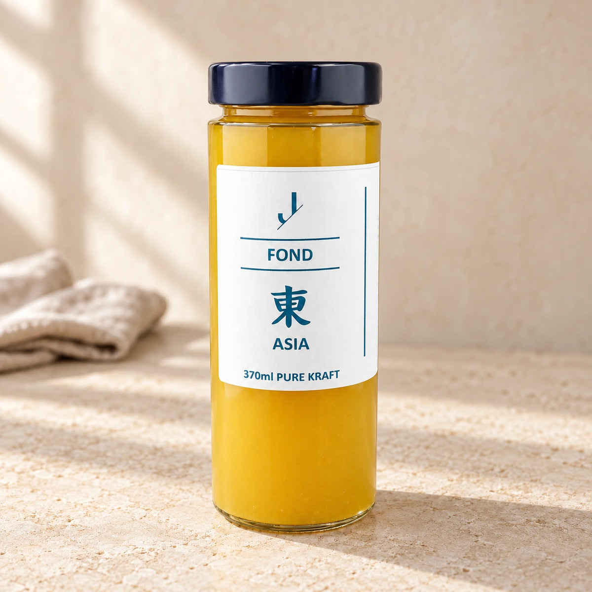 Asia-Fond von Jungermann Gourmet im hohen Glas mit dunklem Deckel und weißem Etikett auf hellem Naturstein.