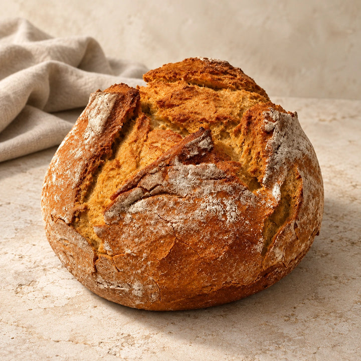 Backhaus-Laib von Jungermann Gourmet als ganzer runder Brotlaib mit kräftiger, unregelmäßig aufgerissener Kruste auf hellem Naturstein.