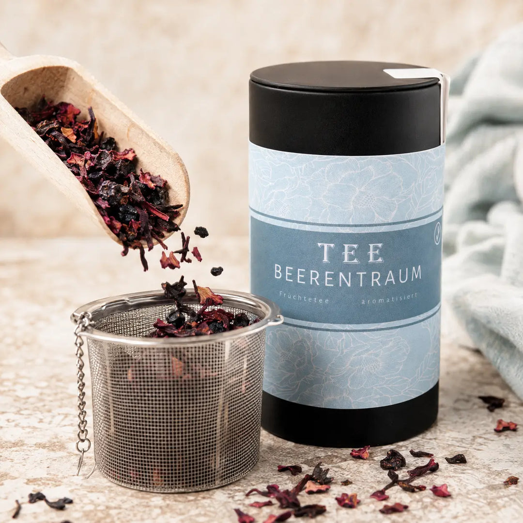 Beerentraum Früchte Tee Mischung fällt in ein Teesieb neben der Dose