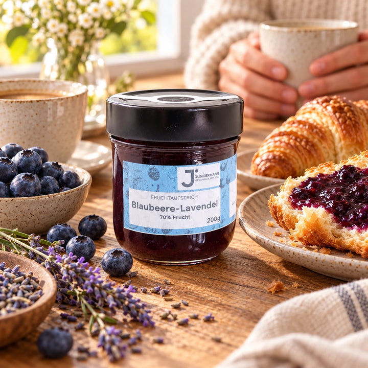Frühstückstisch mit Blaubeere-Lavendel Fruchtaufstrich, bestrichenem Buttercroissant, Kaffee und frischen Blaubeeren