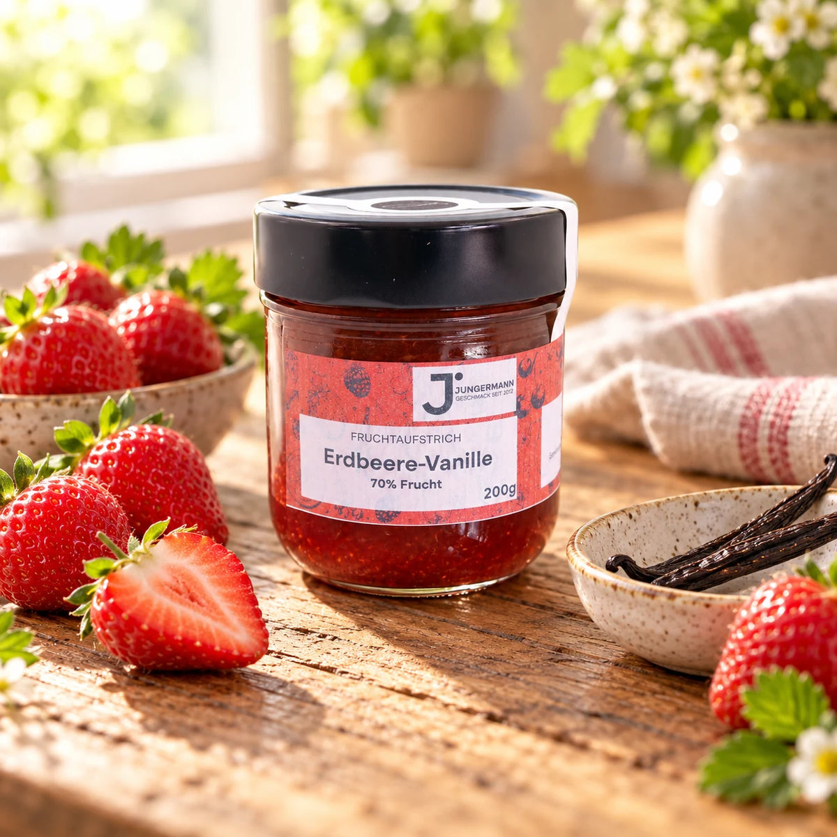 Erdbeere-Vanille Fruchtaufstrich im Originalglas auf rustikalem Holz mit frischen Erdbeeren und Bourbon-Vanilleschoten als Zutaten