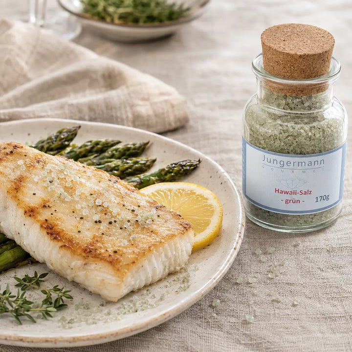 Gegrillter weißer Fisch mit Spargel neben dem originalen Glas mit grünem Hawaii-Salz