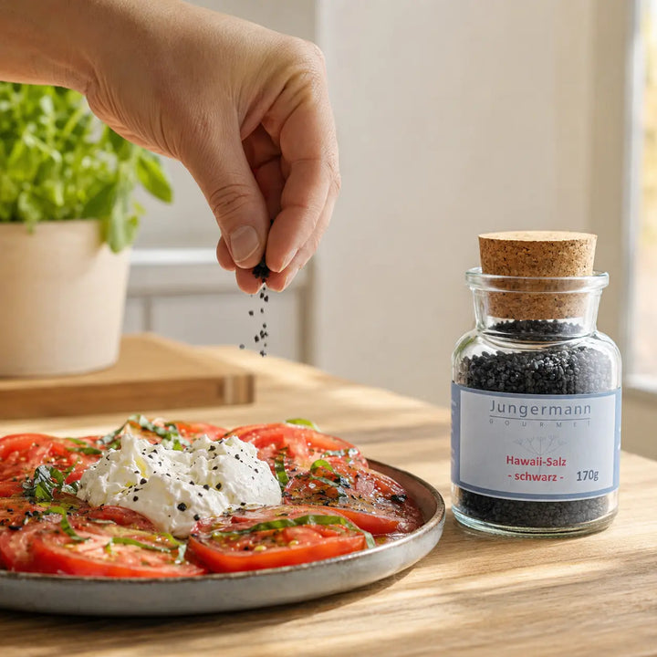 Schwarzes Hawaii-Salz wird über Tomaten mit Burrata gestreut