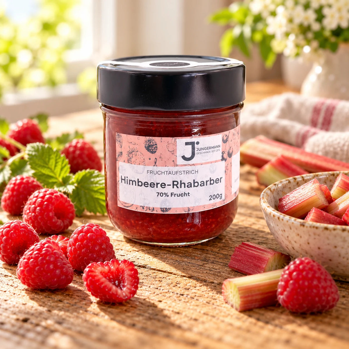 Himbeere-Rhabarber Fruchtaufstrich im Originalglas auf rustikalem Holz mit frischen Himbeeren und Rhabarberstücken als Zutaten
