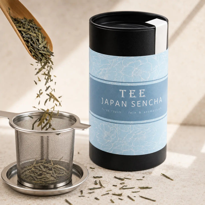 Lose Japan Sencha Teeblätter fallen in ein Edelstahl-Teesieb neben der Dose