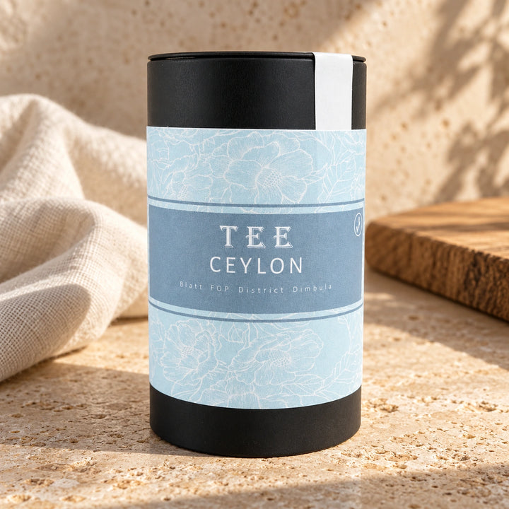 Ceylon-Tee von Jungermann Gourmet in der schwarzen Dose mit hellblauem Etikett auf hellem Naturstein.
