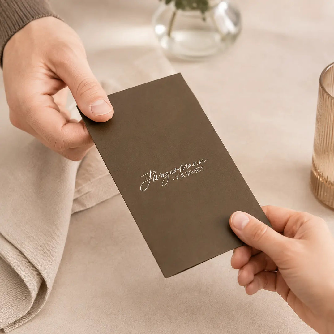 Jungermann Gourmet Geschenk-Gutschein in brauner Hülle bei der Übergabe