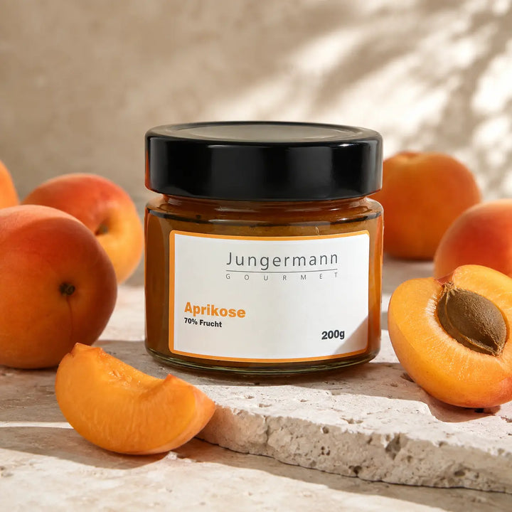 Aprikosen Aufstrich von Jungermann Gourmet mit reifen Aprikosen auf hellem Stein