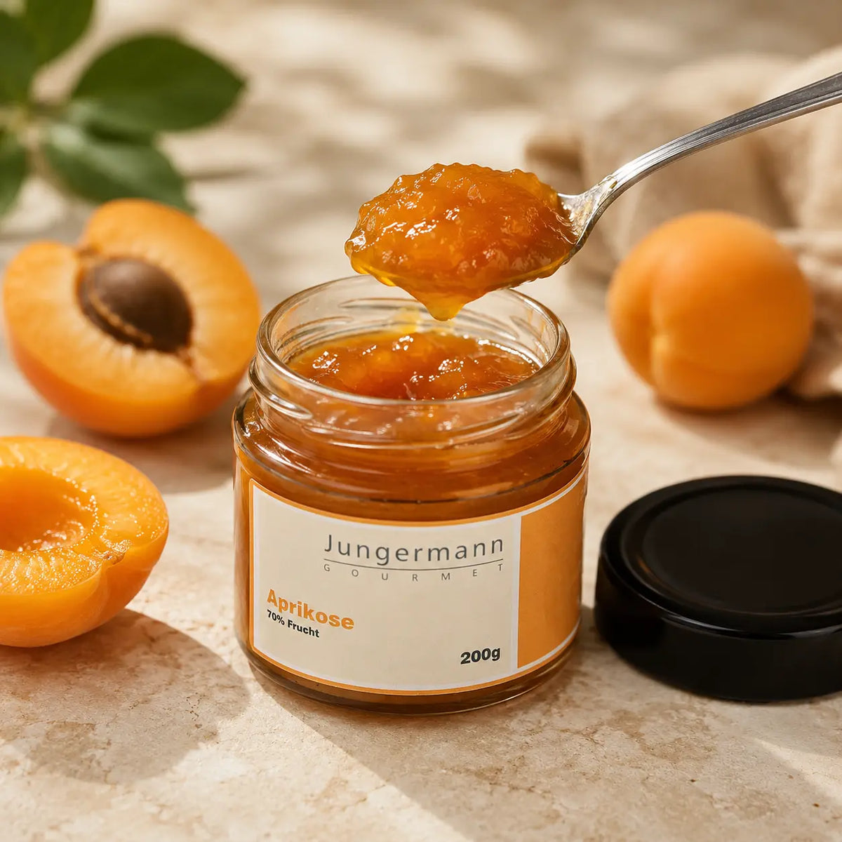 Geöffneter Aprikosen Aufstrich von Jungermann Gourmet mit Löffel und frischen Aprikosen