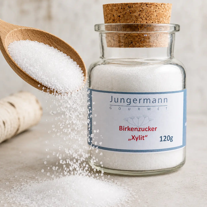Weiße Birkenzucker-Xylit-Kristalle auf einem Holzlöffel neben dem Produktglas