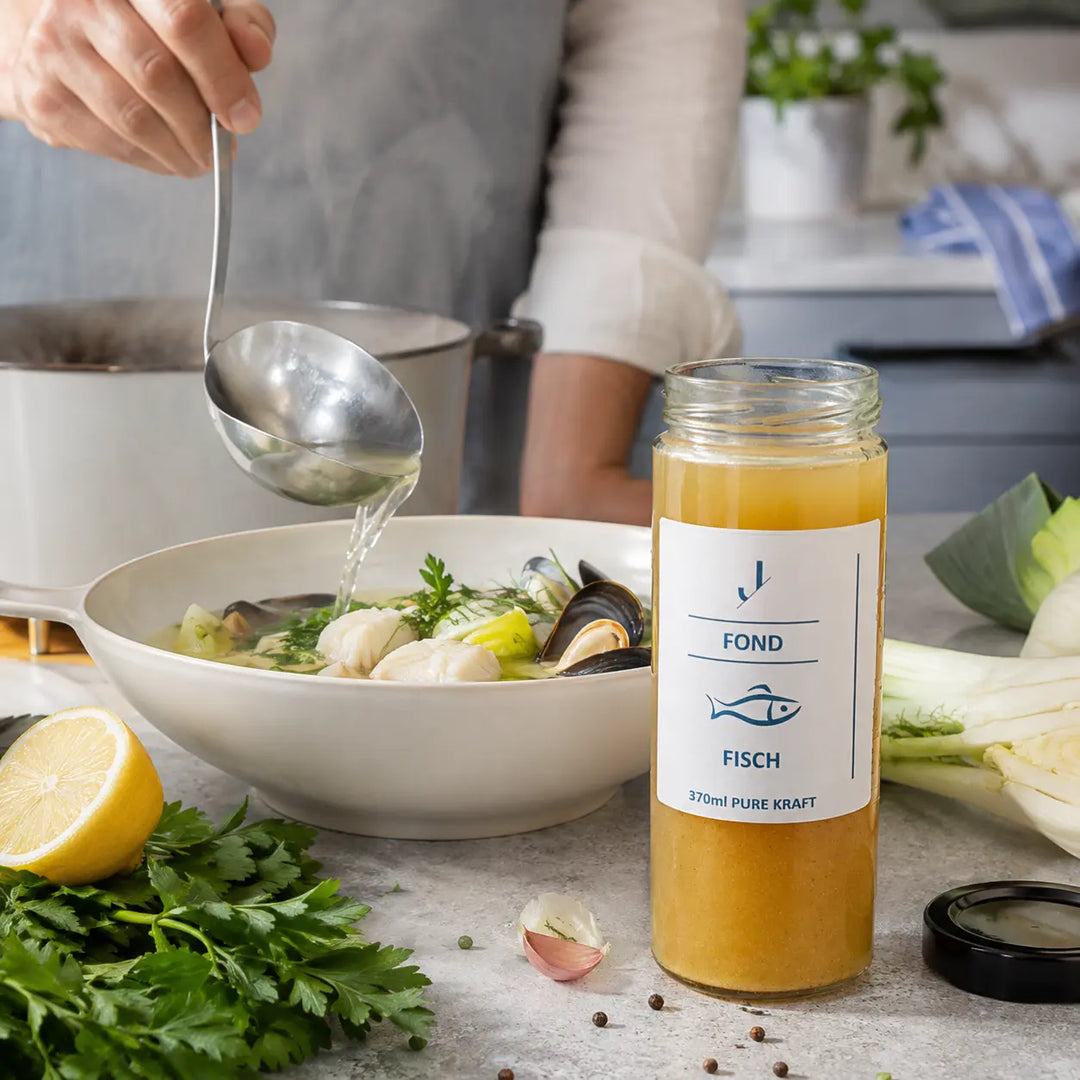 Fisch-Fond beim Anrichten einer leichten Fischsuppe mit Fenchel, Muscheln und Petersilie