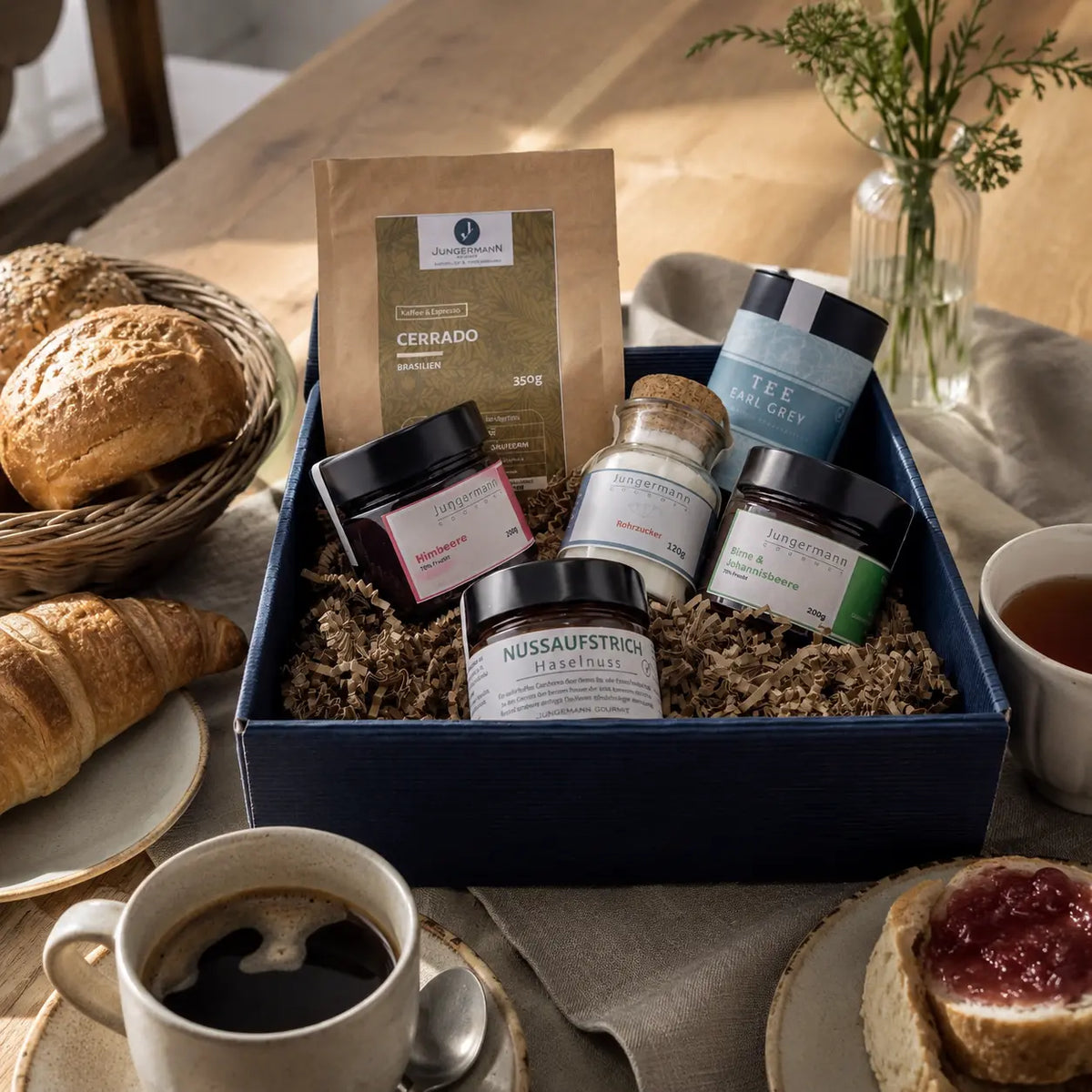 Frühstücks-Box von Jungermann Gourmet – auf einem gedeckten Frühstückstisch mit Kaffee und Gebäck
