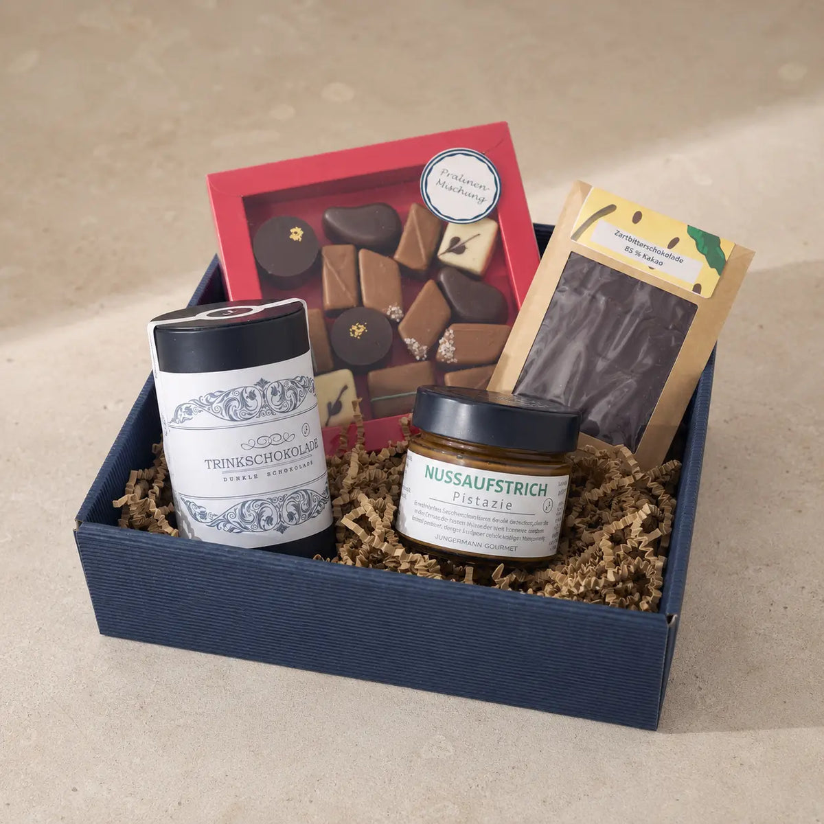 Für Schokoholics von Jungermann Gourmet – geöffnete Geschenkbox mit Pralinen, Zartbitterschokolade, Trinkschokolade und Pistazien-Nussaufstrich
