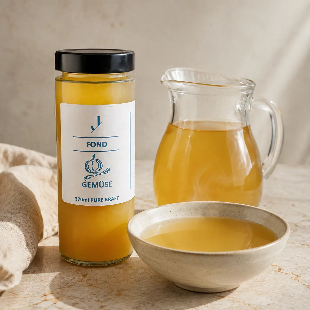 Gemüse-Fond von Jungermann Gourmet – heller Gemüsefond in Glaskaraffe und Keramikschale