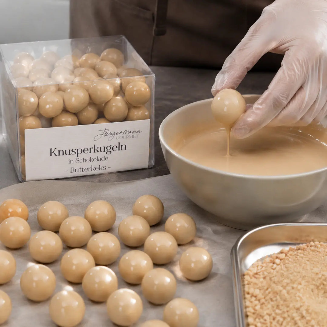Butterkeks-Knusperkugeln beim Überziehen mit heller Schokolade