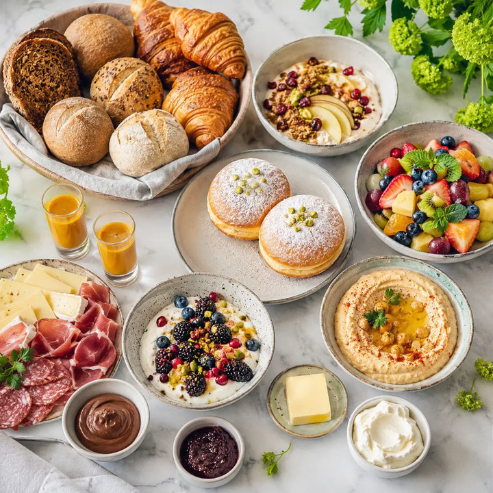 Neujahrs-Brunch-Auswahl mit Gebäck, Krapfen, Obst, Quark, Hummus, Aufstrichen und Ingwer-Kurkuma-Shots