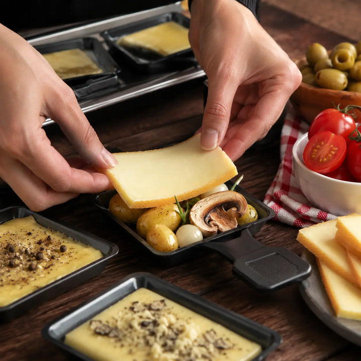 Raclettekäse beim Belegen von Rosmarinkartoffeln und gegrillten Champignons
