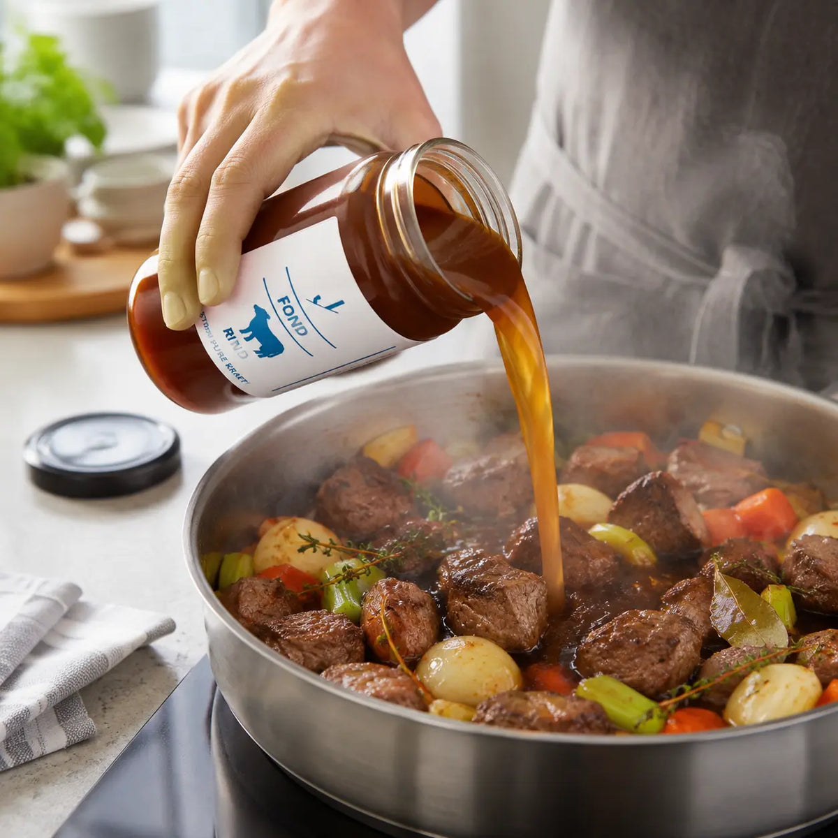 Rinder-Fond beim Angießen von Rindfleisch mit Zwiebeln, Karotten, Sellerie und Thymian
