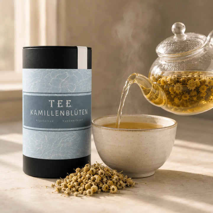 Goldener Kamillenblüten Tee wird aus einer Glaskanne in eine Keramiktasse gegossen