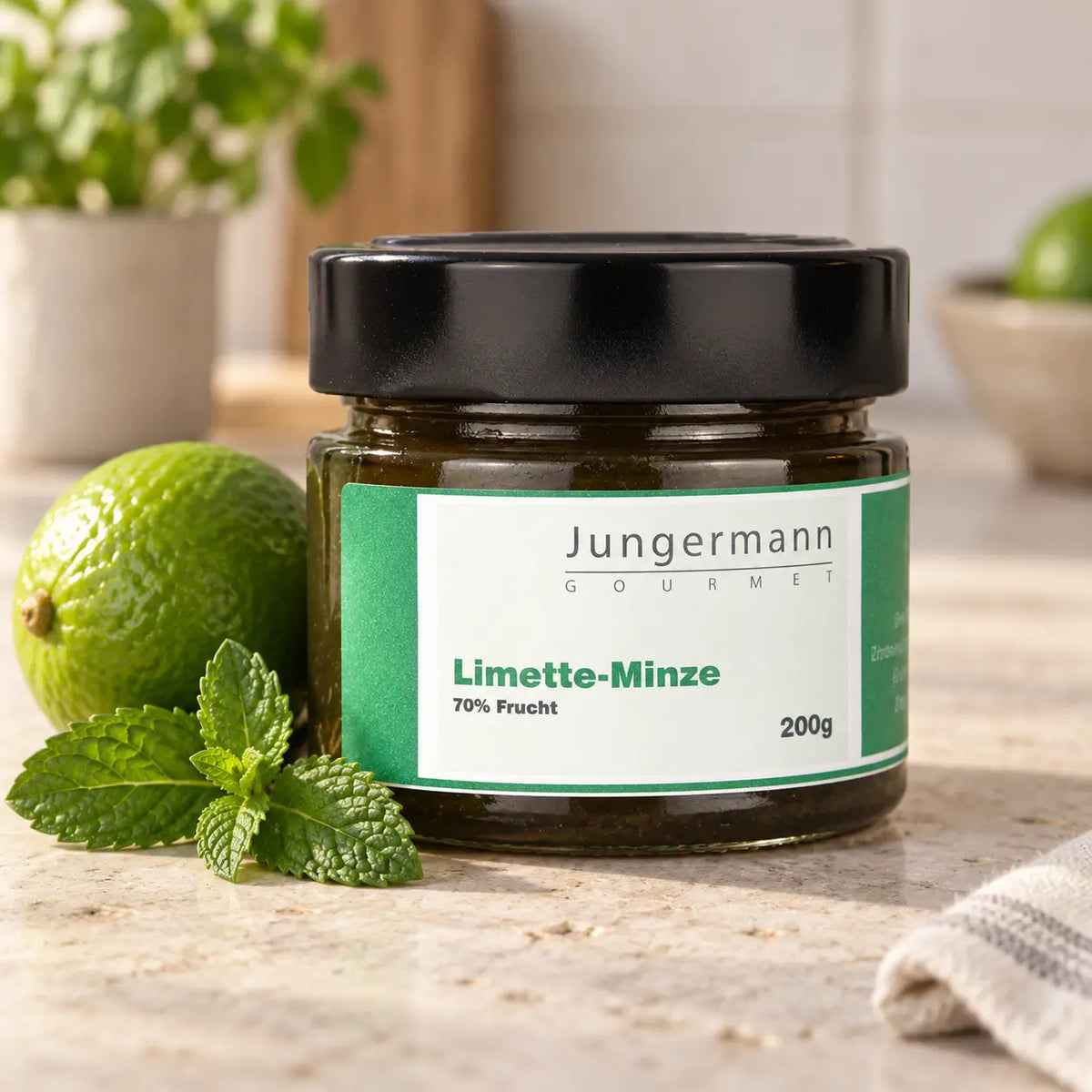 Limetten-Minze-Aufstrich 200 g von Jungermann Gourmet im Glas neben Limette und Minze.