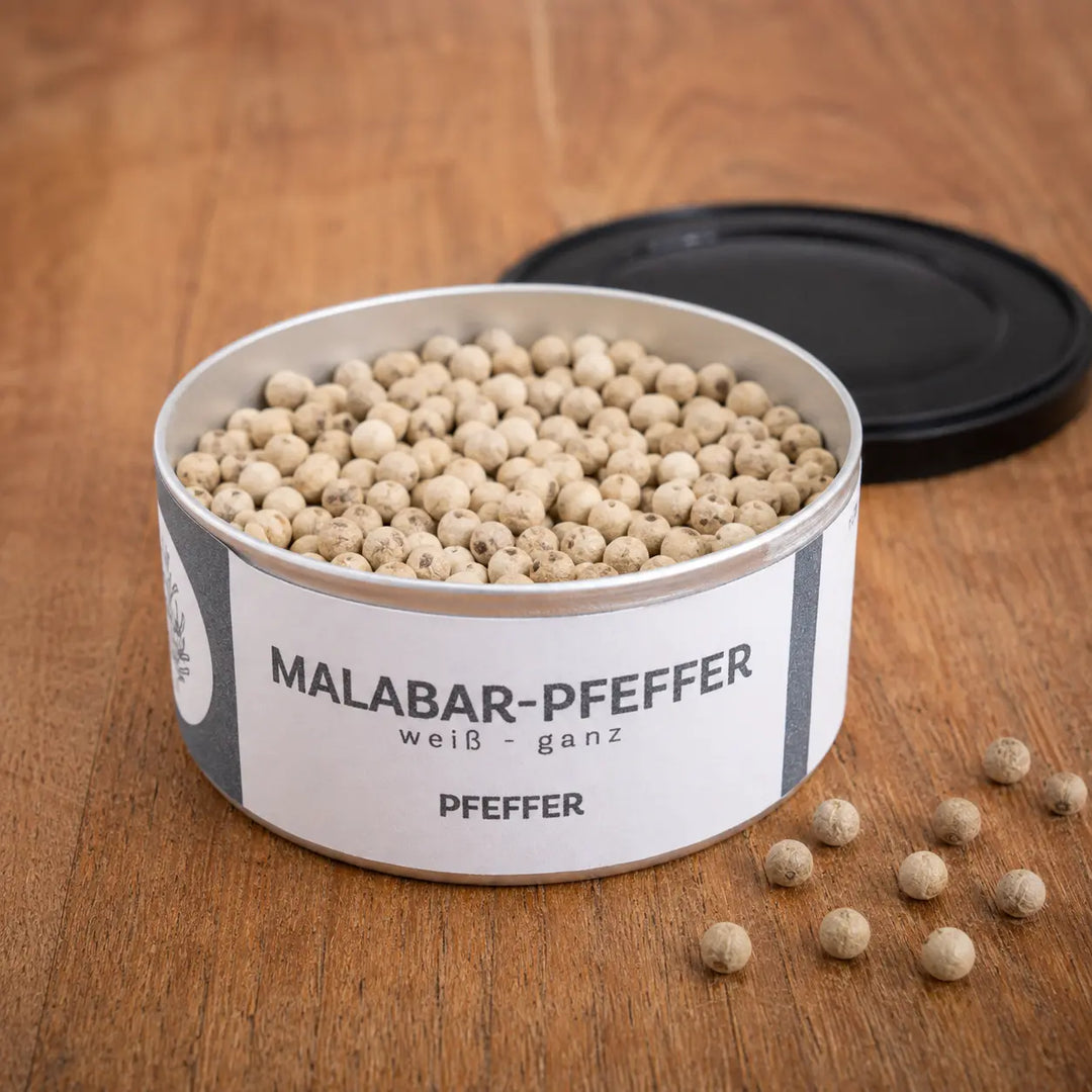 Geöffnete Dose Malabar Pfeffer mit ganzen hellen Pfefferkörnern