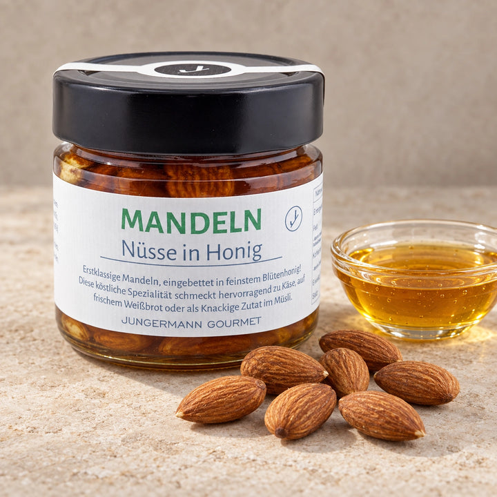 Mandeln in Honig von Jungermann Gourmet im geschlossenen Originalglas, daneben naturbelassene Mandelkerne und eine kleine Glasschale mit Blütenhonig