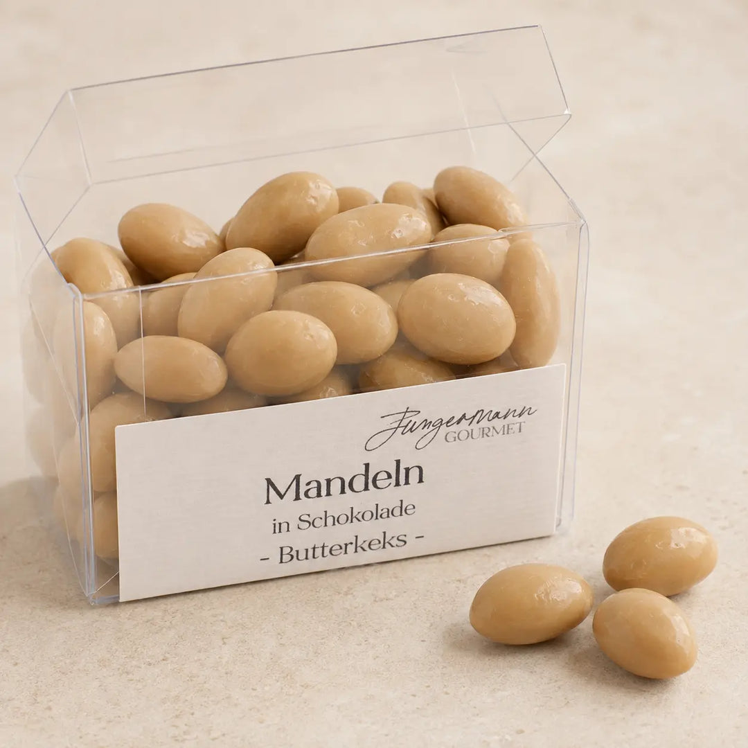 Geöffnete Klarsichtbox mit hellen Mandeln in Schokolade Butterkeks