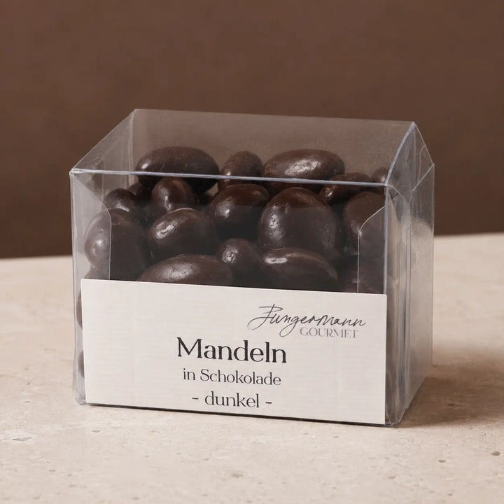 Dunkle Mandeln in Schokolade in der originalen Klarsichtbox als Packshot