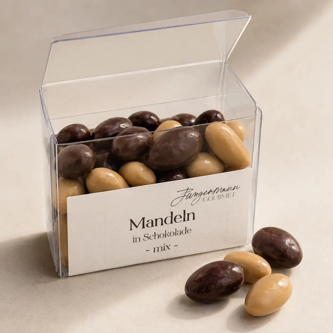 Geöffnete Klarsichtbox mit hellen und dunklen Mandeln in Schokolade