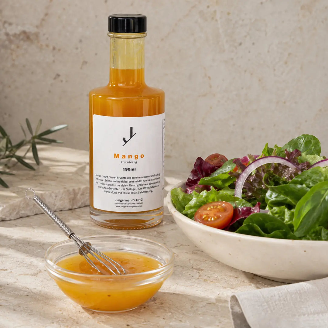 Mango Essig neben frisch angerührtem Dressing und Blattsalat