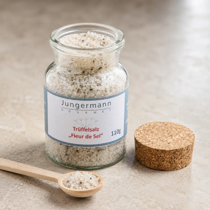Geöffnetes Korkenglas mit grobem Trüffelsalz und kleinem Salzlöffel