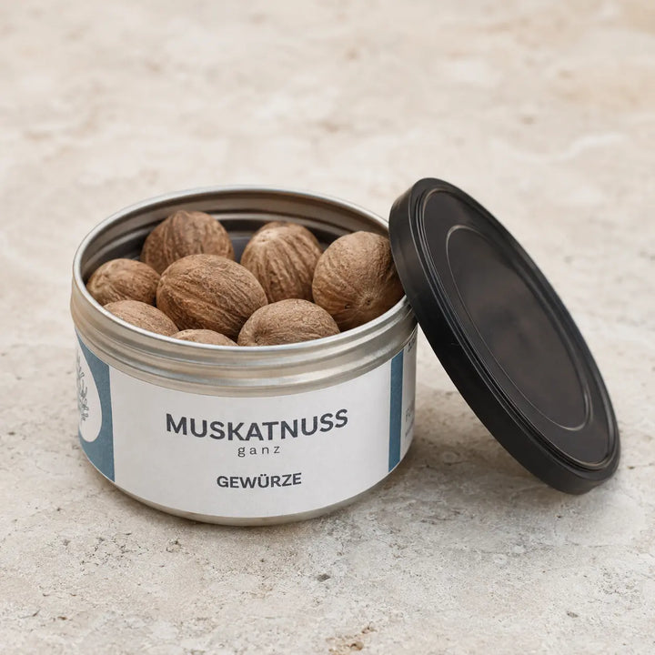 Geöffnete originale Gewürzdose mit ganzen Muskatnüssen und schwarzem Deckel