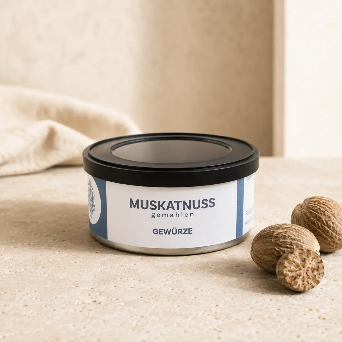 Muskatnuss gemahlen in originaler Gewürzdose als hochwertiger Packshot mit ganzen Muskatnüssen