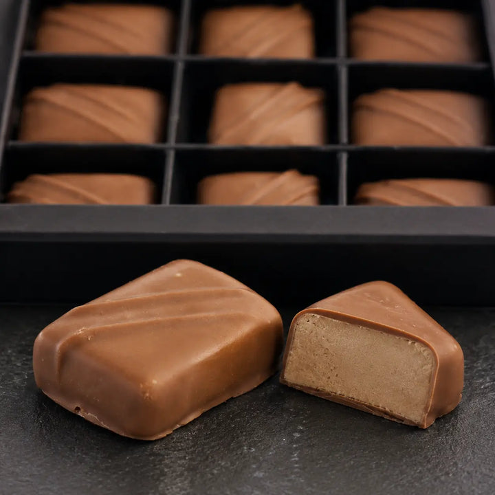 Nougat Praline im Anschnitt mit glatter nussiger Füllung vor der originalen Neunerbox