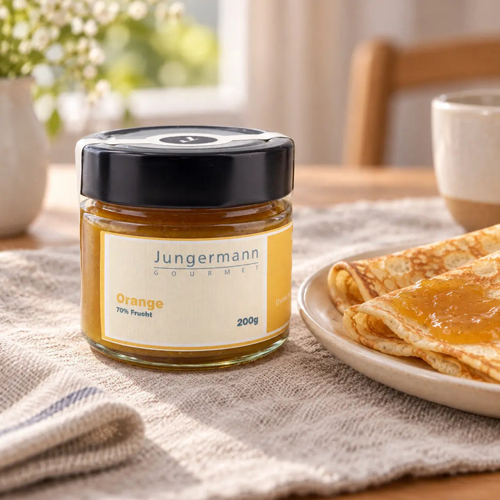 Orangen-Aufstrich von Jungermann Gourmet im Originalglas neben Crêpes mit Aufstrich als süßer Serviervorschlag.