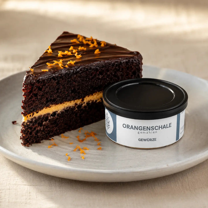 Schokoladenkuchen mit Orangennote neben der originalen Dose gemahlener Orangenschale