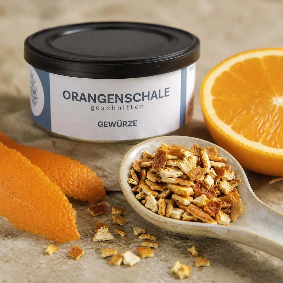 Grob geschnittene getrocknete Orangenschale auf Keramiklöffel mit frischer Orange