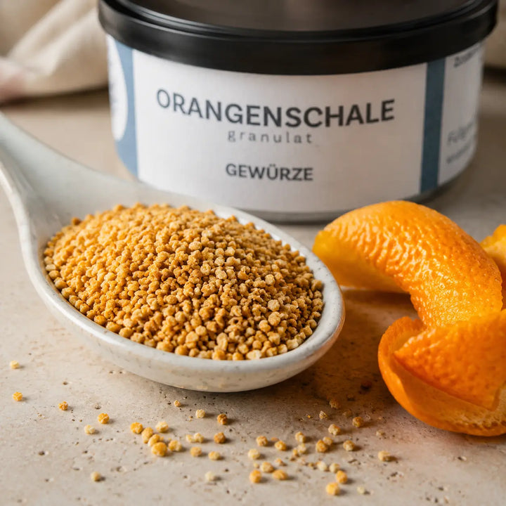 Feines Orangenschalen-Granulat auf Keramiklöffel mit frischer Orangenschale