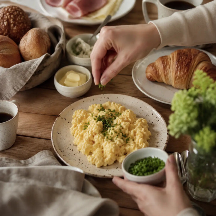 Cremiges Rührei wird am Brunch-Tisch mit frischem Schnittlauch vollendet