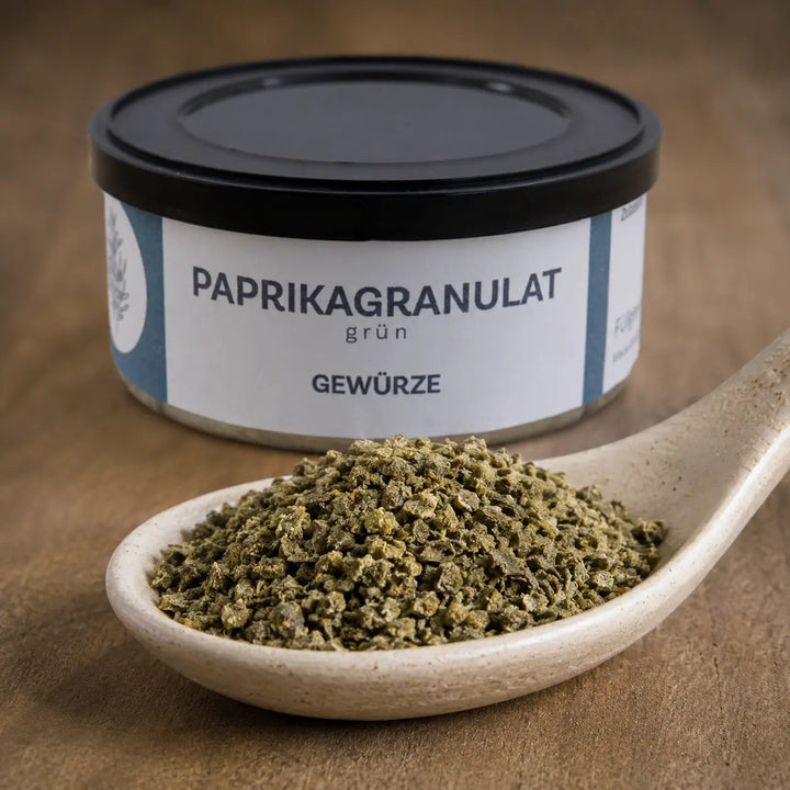 Grobes grünes Paprikagranulat im Detail vor der originalen Gewürzdose