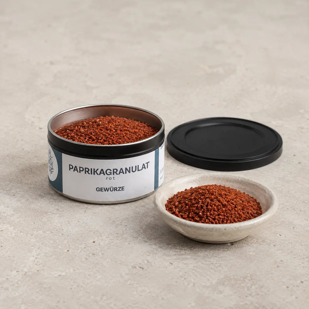 Geöffnete Originaldose mit grobem rotem Paprikagranulat und schwarzem Deckel