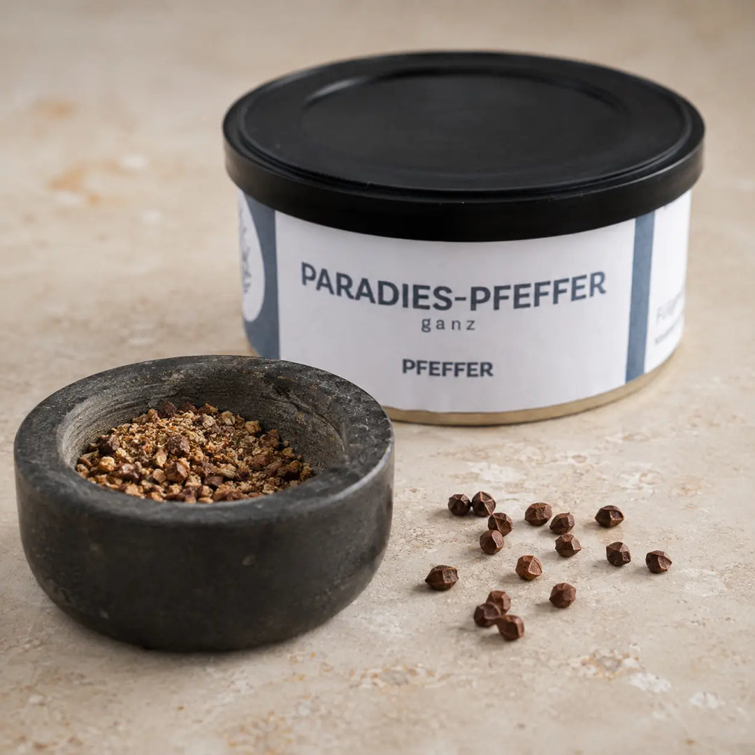 Ganze und frisch zerstoßene Paradieskörner im Mörser vor der originalen Gewürzdose