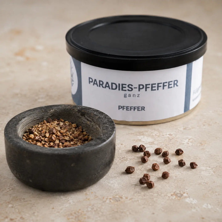Ganze und frisch zerstoßene Paradieskörner im Mörser vor der originalen Gewürzdose