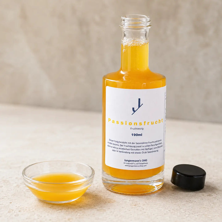 Geöffnete Originalflasche mit gelb-orangefarbenem Passionsfrucht Essig und Probeschale