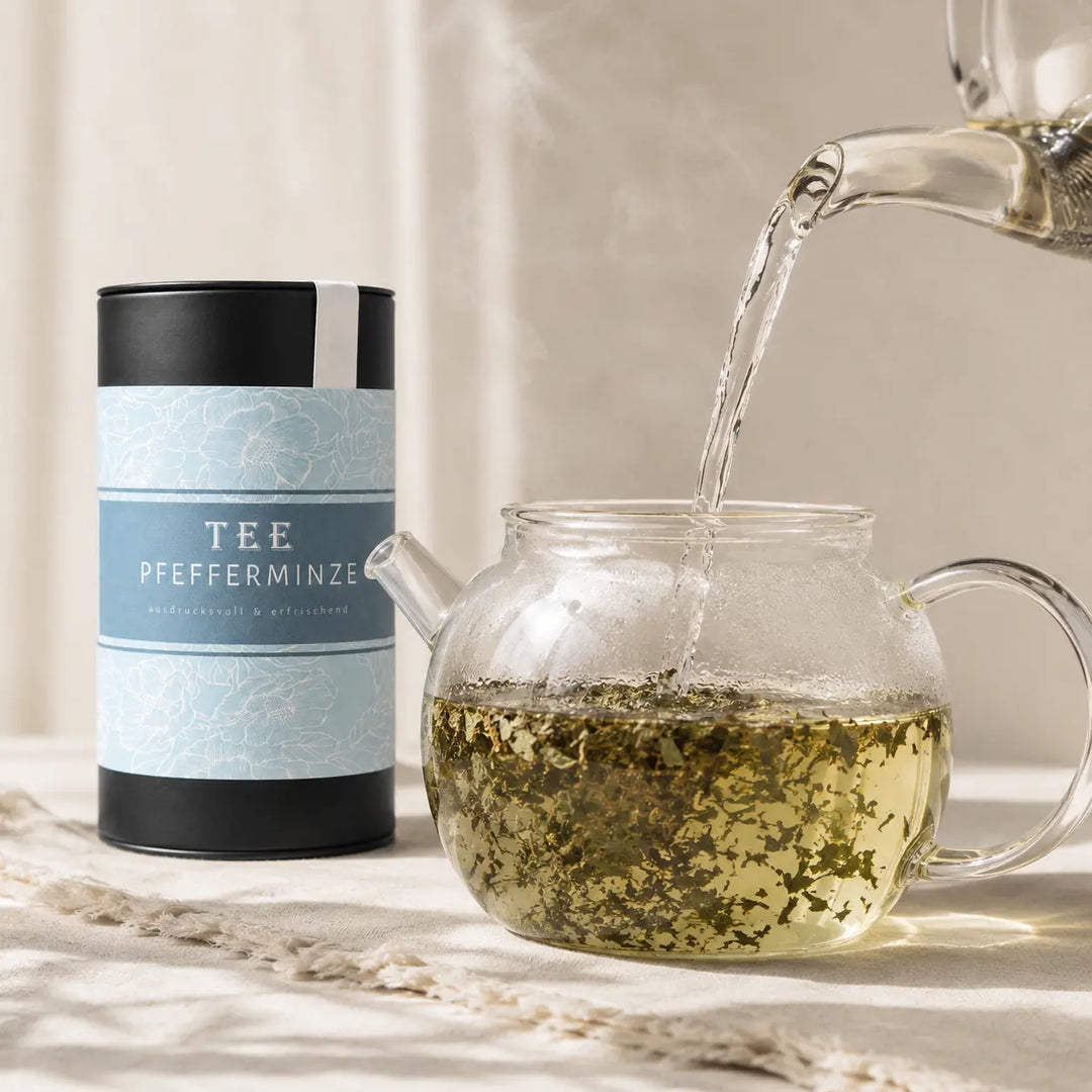Pfefferminze Tee wird mit heißem Wasser in einer Glasteekanne aufgegossen